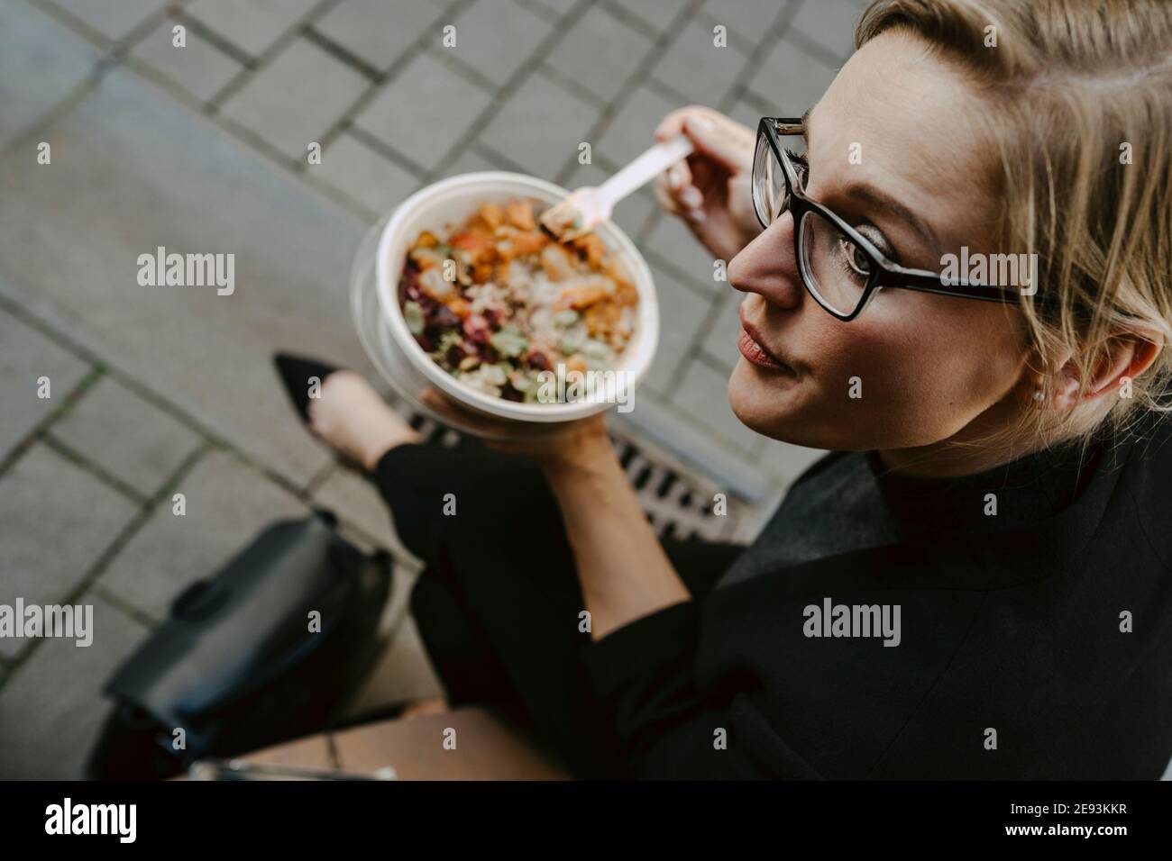 Donna imprenditore con insalata ciotola guardando via Foto Stock