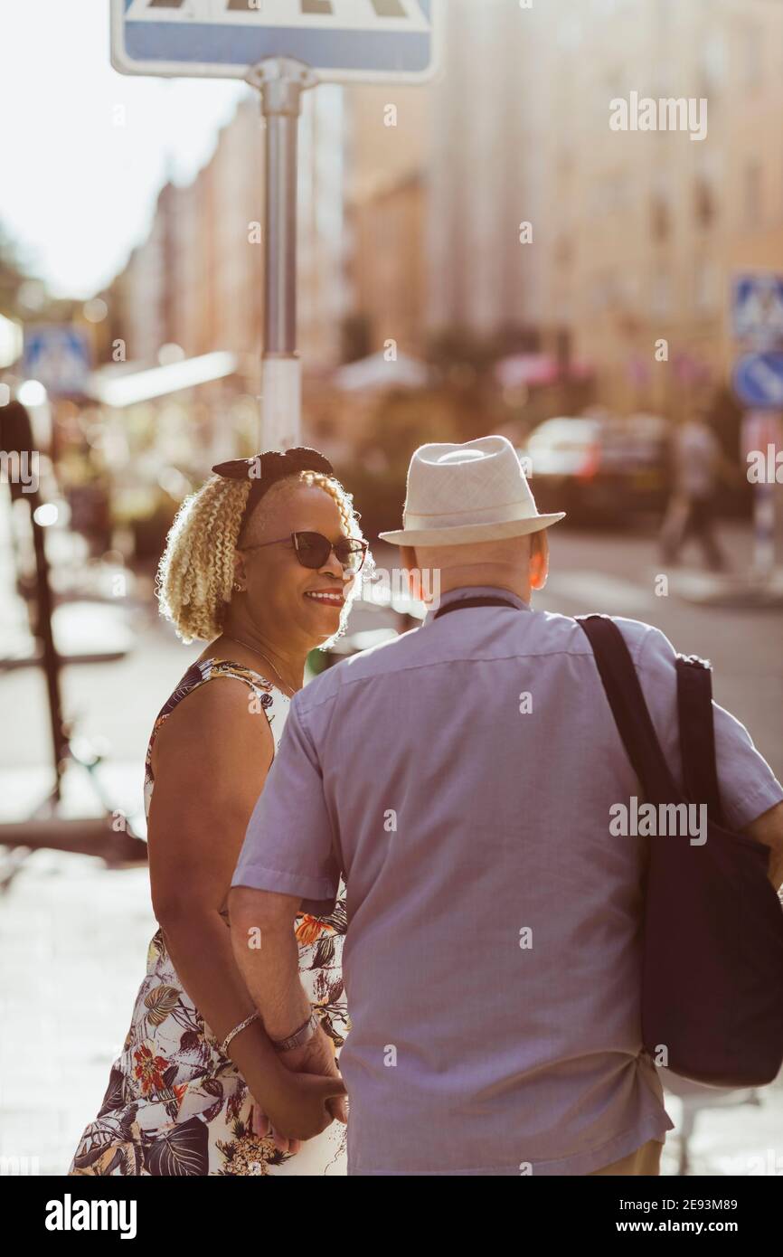 Donna sorridente che guarda l'uomo anziano mentre esplorando la città durante vacanza Foto Stock