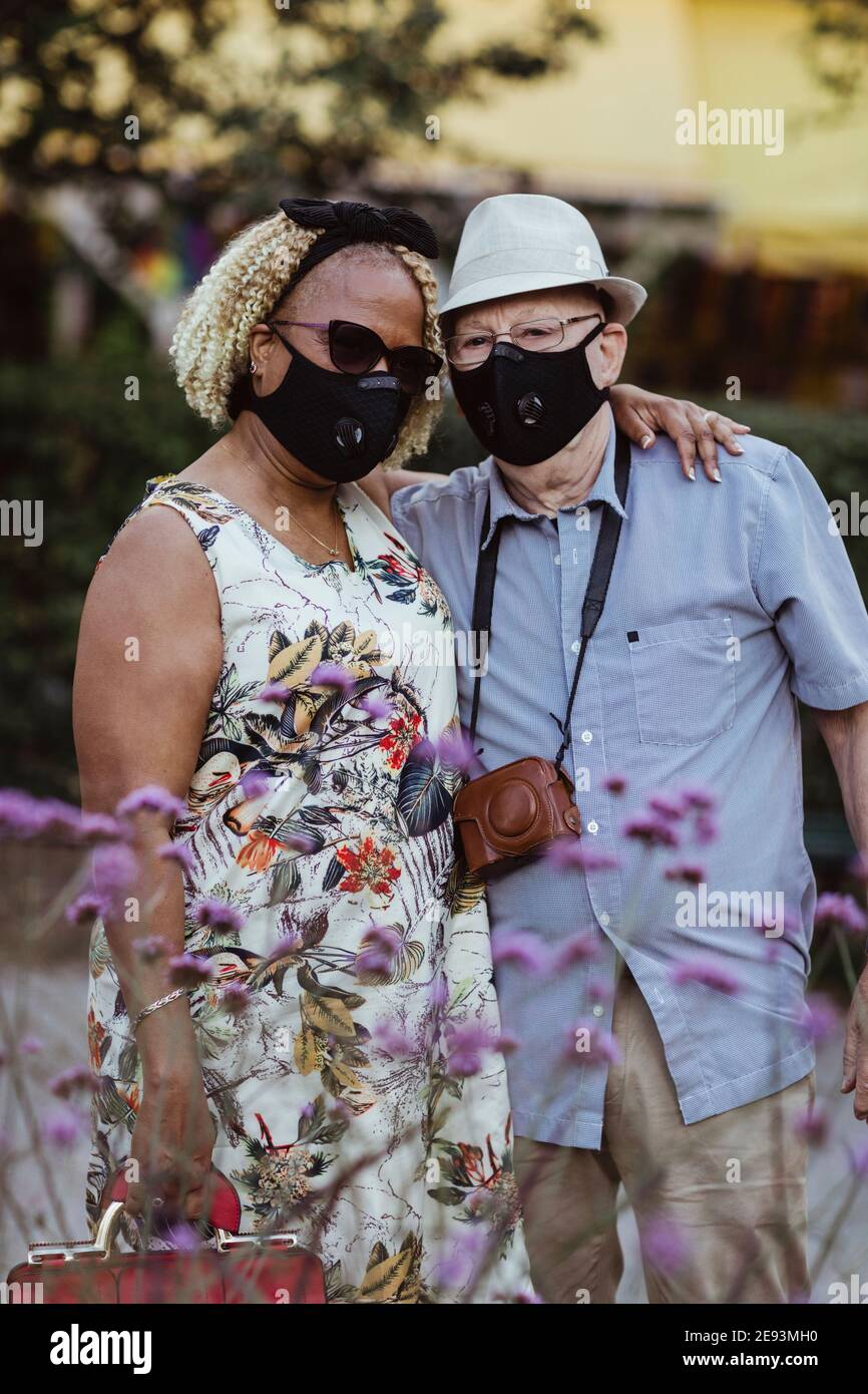 Coppia eterosessuale con braccio intorno in piedi nel parco durante la pandemia Foto Stock