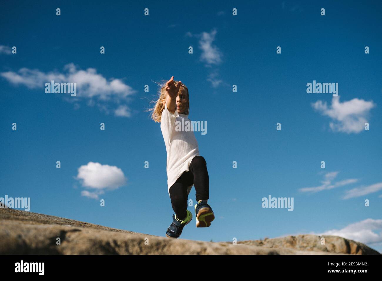 Vista ad angolo basso della ragazza che salta sulle rocce Foto Stock