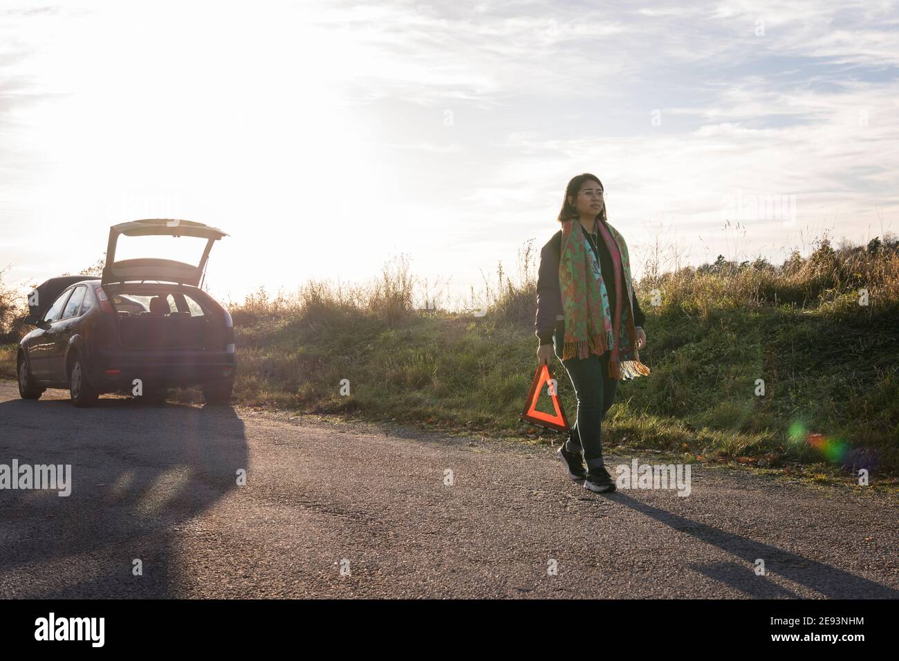 Donna su strada che tiene il triangolo di avvertimento Foto Stock