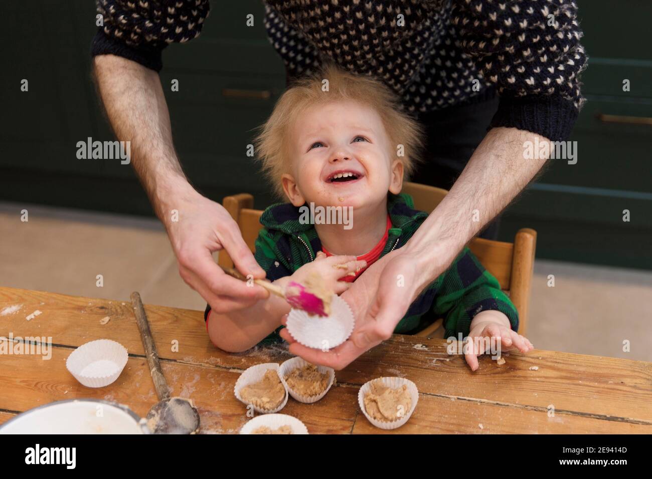Un bambino giovane che si diverte ad aiutare il suo papà cuocere le torte in cucina. Foto Stock