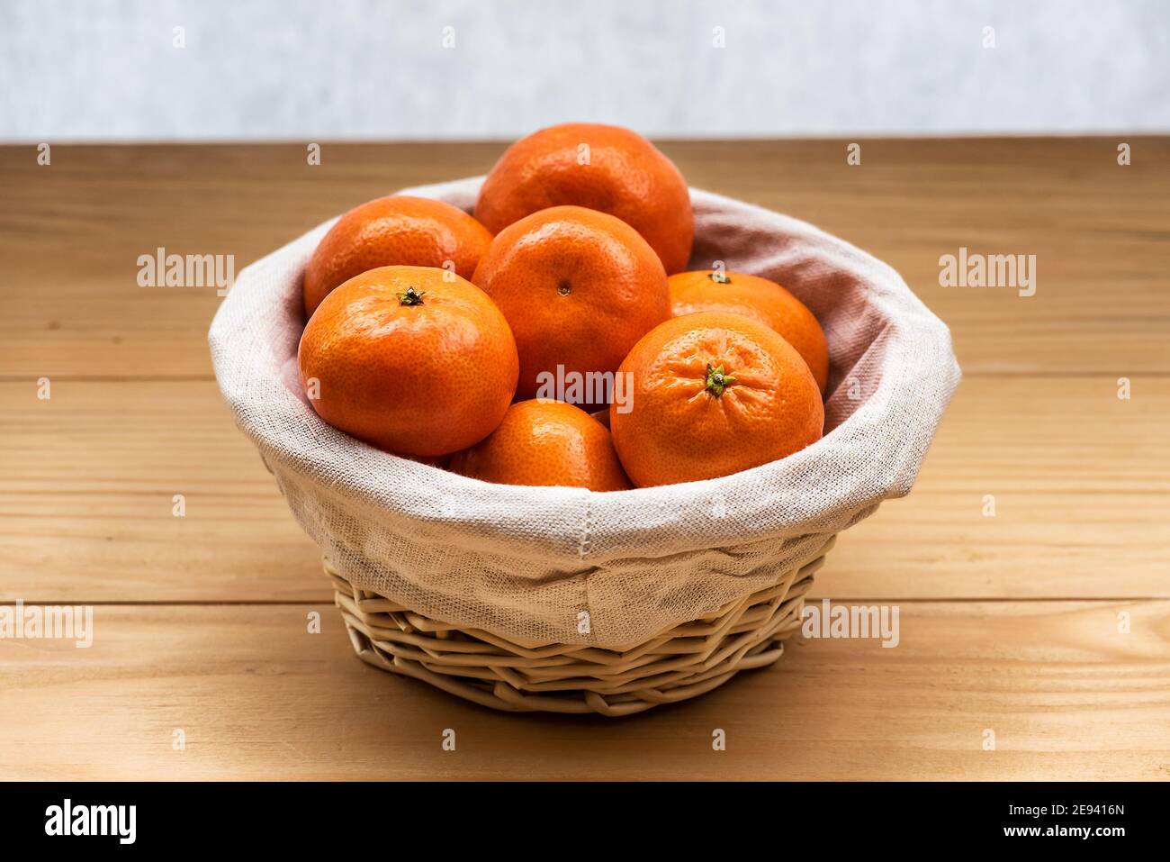 Tangerini (arance, clementine, agrumi) in un cesto di vimini su sfondo di legno con spazio per la copia Foto Stock