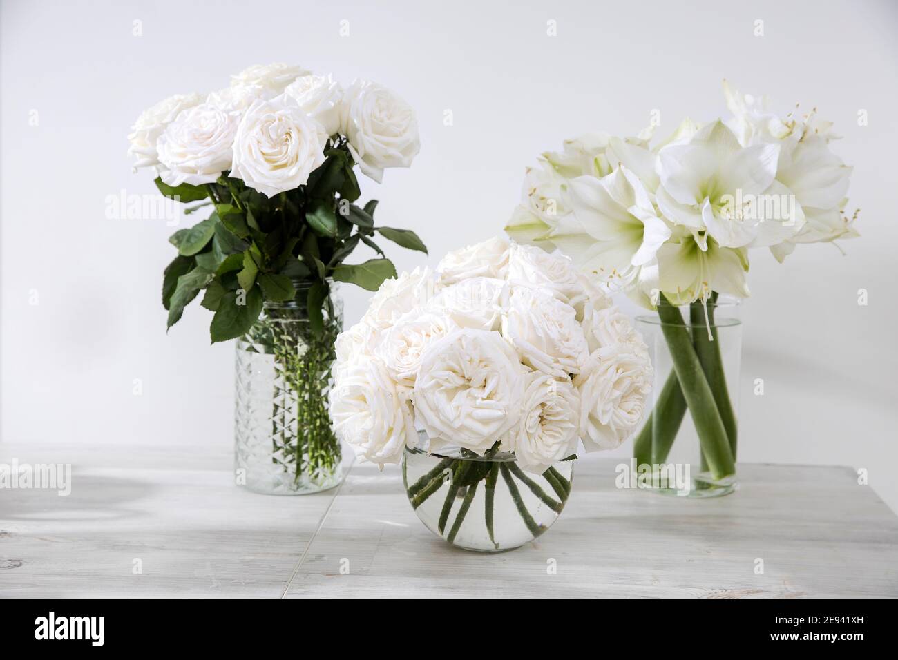 Rose bianche, giglio, in vasi rotondi con due tazze di caffè sul tavolo per un'occasione speciale come decorazione della cucina. Spazio di copia Foto Stock Rose bianche, giglio, in vasi rotondi con due tazze di caffè sul tavolo per un'occasione speciale come decorazione della cucina. Spazio di copia Foto Stock