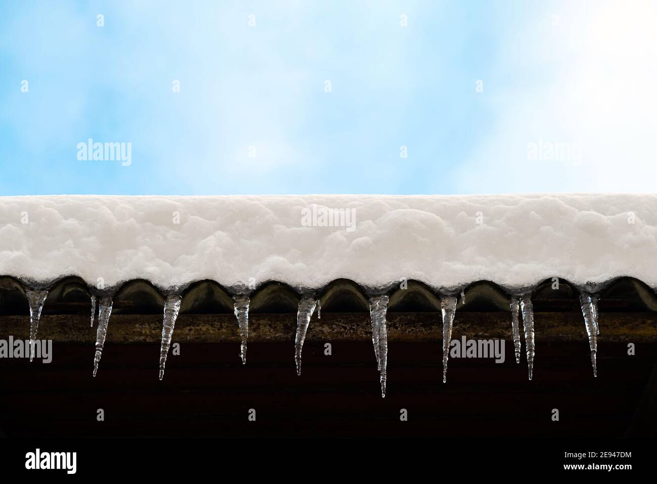 Piciclette affilate appese sul bordo del tetto. Sciogliendo la neve si forma un icicolo. Foto Stock