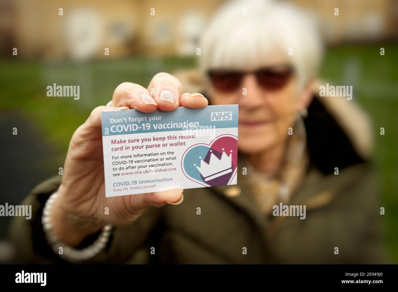 Signora anziana che mostra la sua carta come prova della vaccinazione Covid-19 Foto Stock