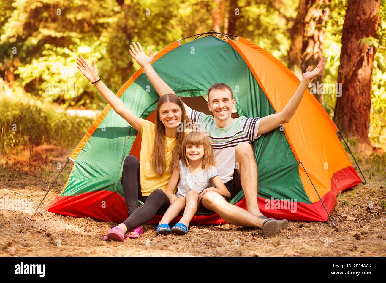 Famiglia di tre persone in campeggio e divertirsi insieme nella foresta estiva. Vacanze in campeggio. Foto Stock