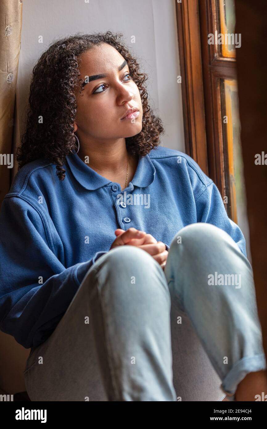 Bellissima gara di misto americano africano ragazza adolescente di sesso femminile donna giovane triste premuto o pensieroso guardando fuori della finestra Foto Stock