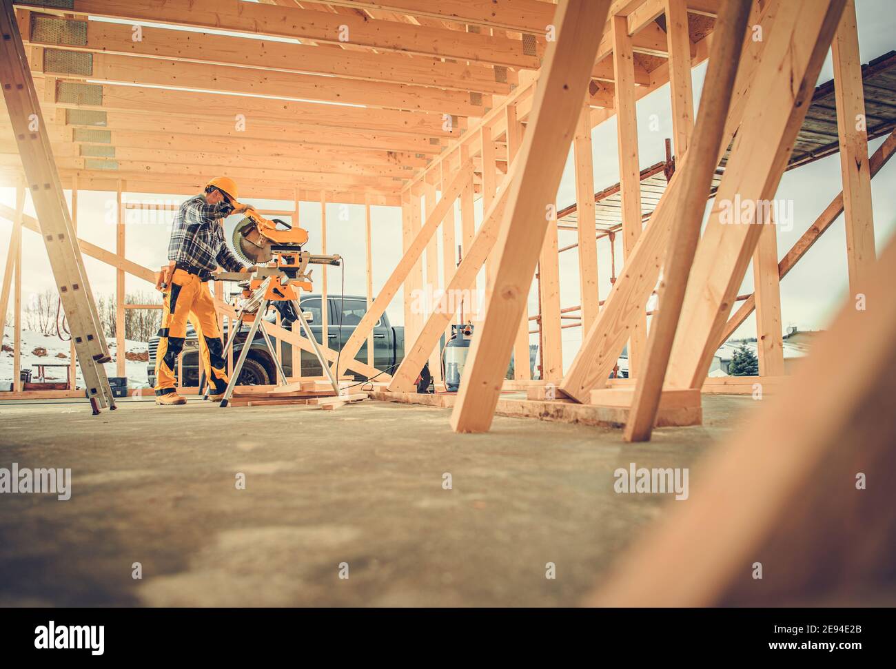 Caucasian Contractor Carpenter Worker nei suoi 40 utilizzando la sega circolare di grado commerciale nella zona di costruzione. Tema industriale. Telaio in legno scheletro B Foto Stock