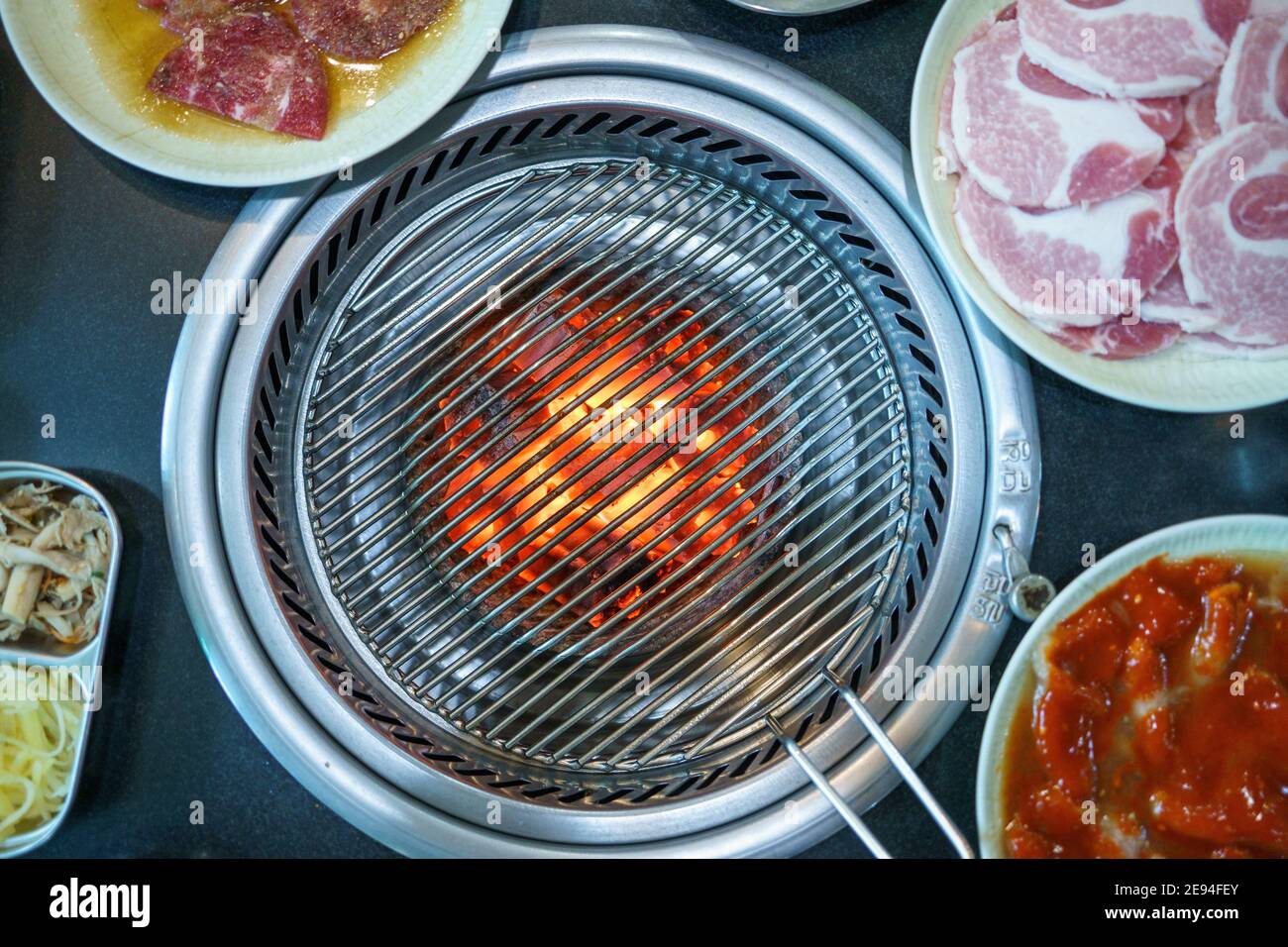 vista dall'alto delle bistecche di carne assortite sulla griglia calda grattugiare con fiamme Foto Stock