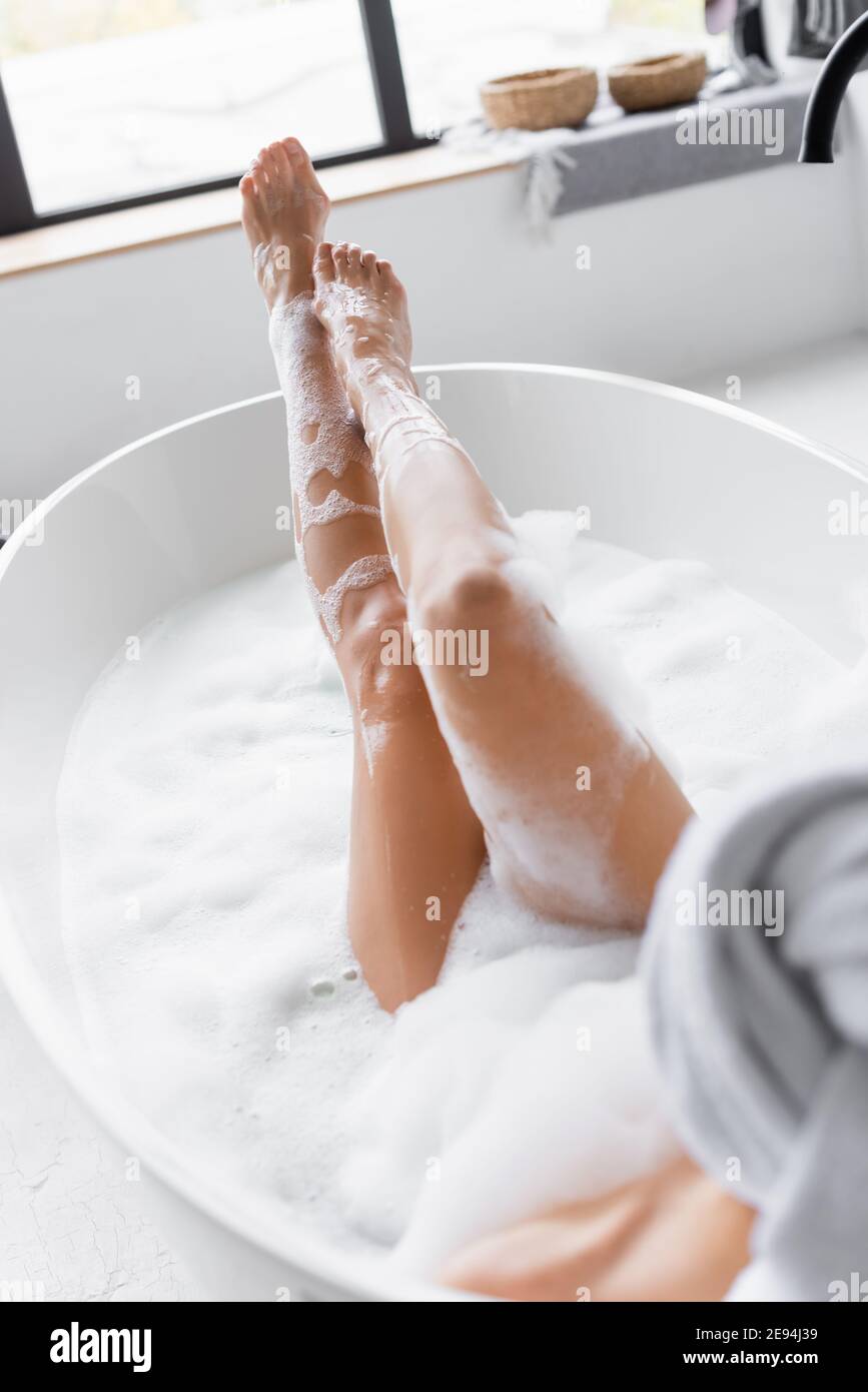 Gambe di giovane donna in schiuma nella vasca da bagno su offuscata primo  piano Foto stock - Alamy