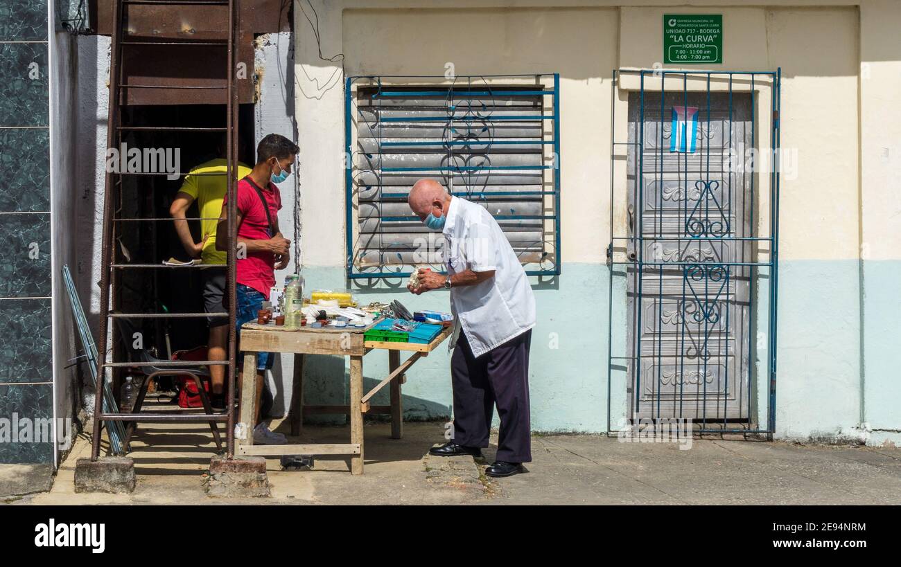 Uomo anziano che acquista piccoli oggetti in un'azienda privata a Santa Clara, Cuba Foto Stock