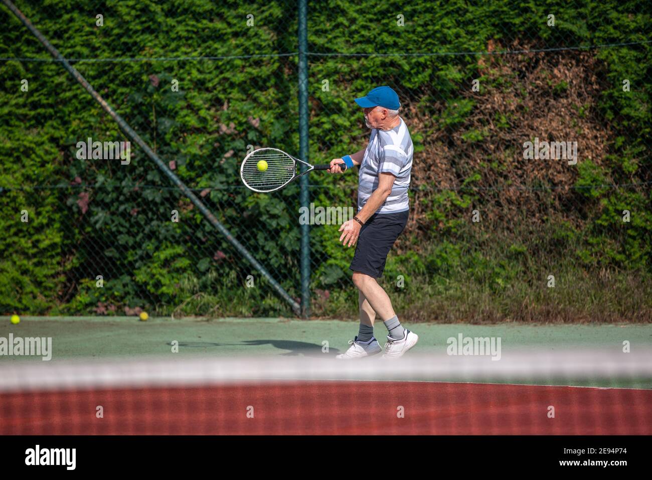 Uomo anziano che gioca a tennis all'aperto sul campo da tennis, concetto sportivo Foto Stock