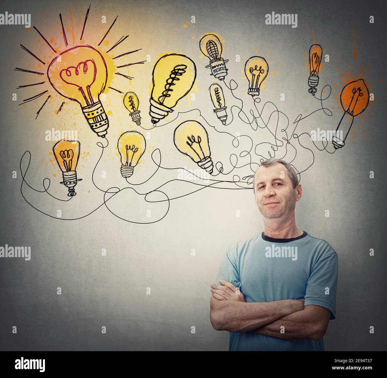L'uomo creativo di mezza età mantiene le braccia incrociate, guardando fiducioso come molteplici grandi idee. Motivato maschio senior e lampade luminose sopra la sua testa Foto Stock