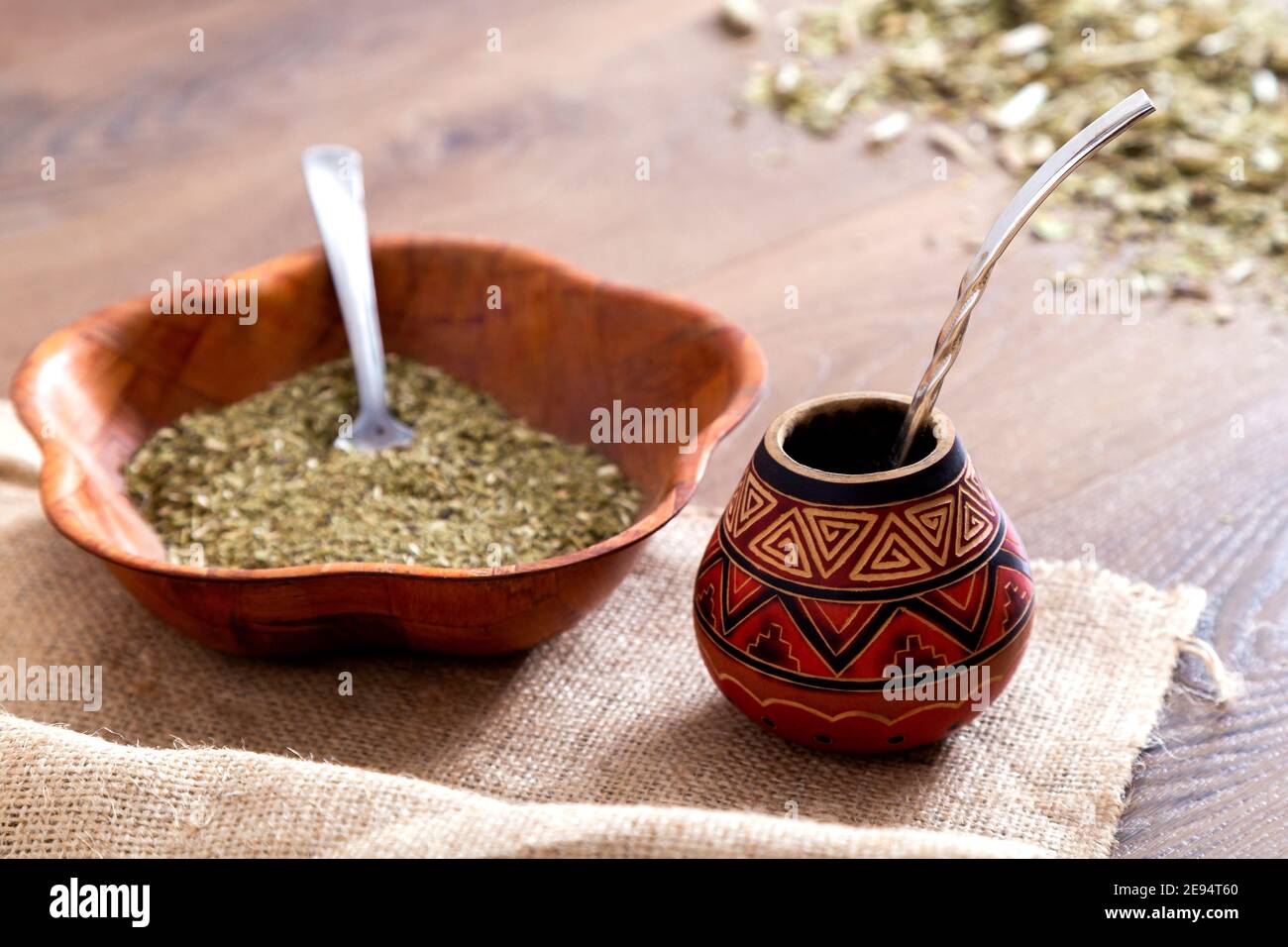 Accoppiamento tradizionale fatto di calabash su un tavolo di legno con yerba mate sparso su di esso. Foto Stock