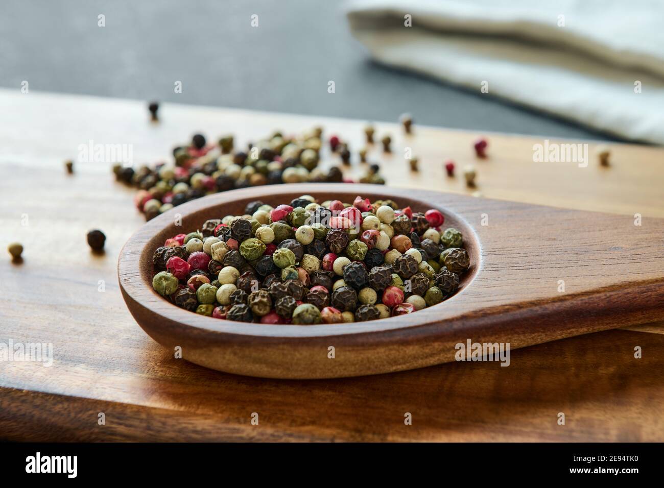 Varietà di peppercorn colorate su un cucchiaio di legno, spezie, macro Foto Stock