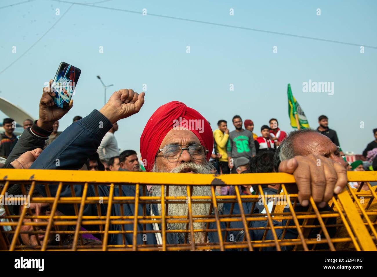 Gli agricoltori si levano in piedi dietro le barriere installate e gridano slogan durante i manifestimentre la protesta degli agricoltori contro i tre atti agricoli continua sul confine di Ghazipur, la polizia di Delhi ha sigillato il confine con barriere, muro di cemento e filo spinato per impedire agli agricoltori di accedervi per le loro proteste. Foto Stock