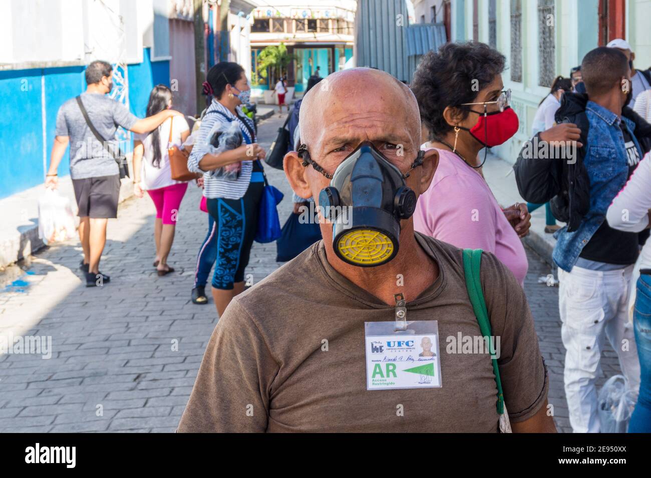 Uomo cubano che indossa una maschera a gas di grado militare mentre si allineano per acquistare il pane a El rapido. È il tempo del Covid-19 a Santa Clara, Cuba Foto Stock