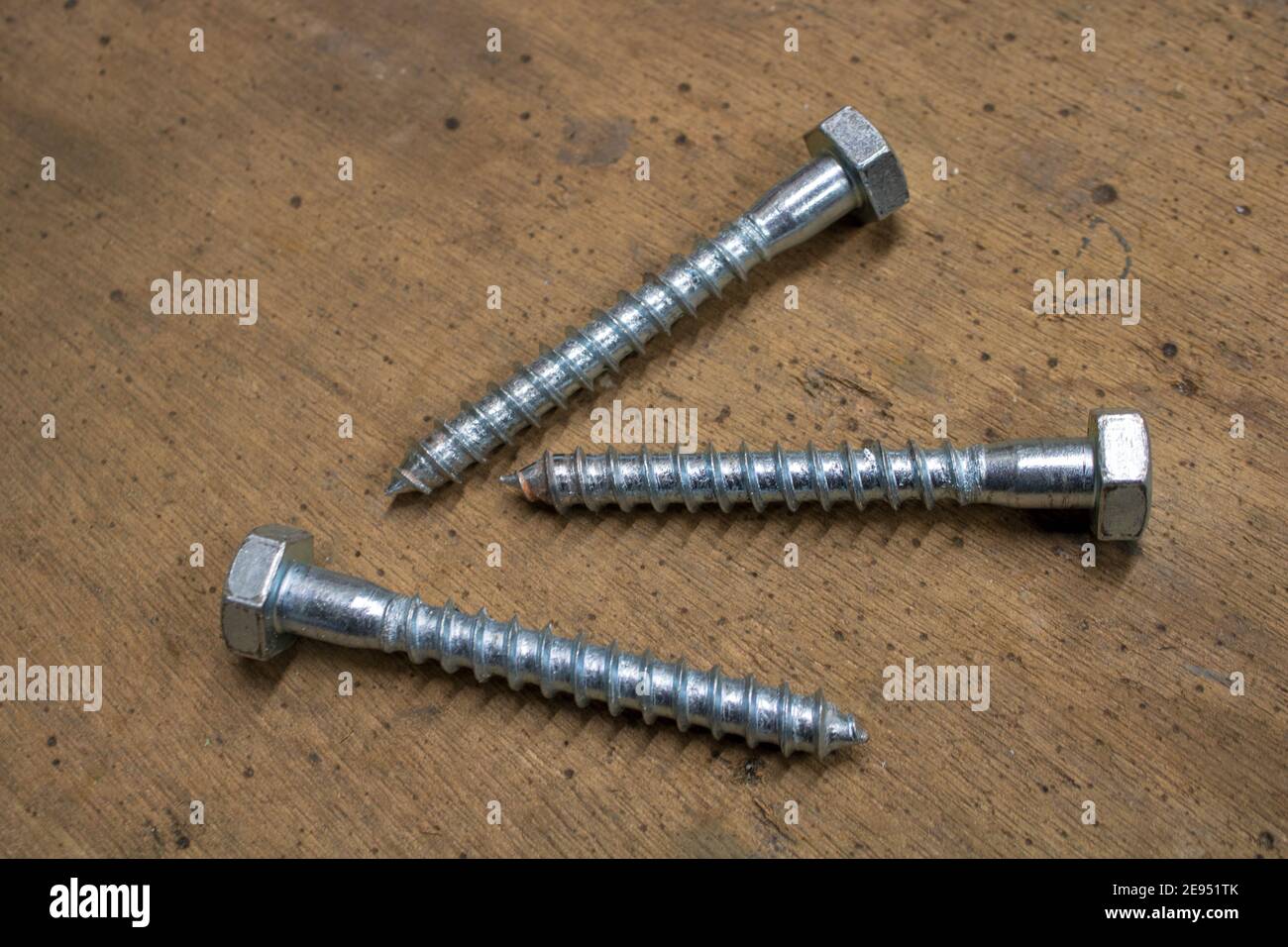 Bulloni a vite ad albero di dimensioni M8 su uno sfondo di legno compensato Foto Stock