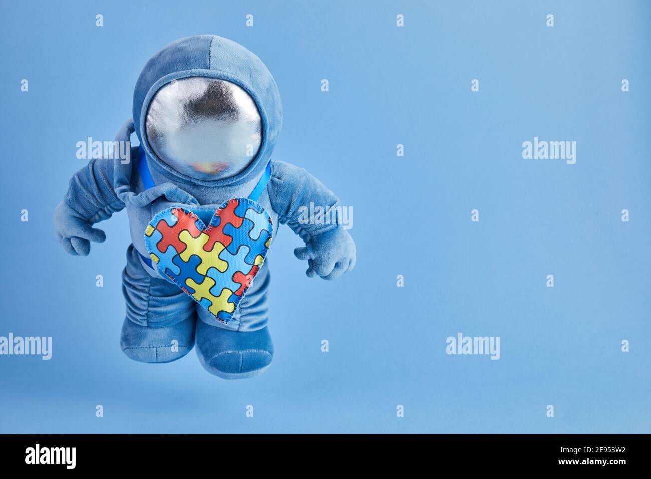 Mondo Autismo consapevolezza giorno background. Peluche blu giocattolo  astronauta con cuore puzzle, simbolo autismo, su sfondo blu Foto stock -  Alamy