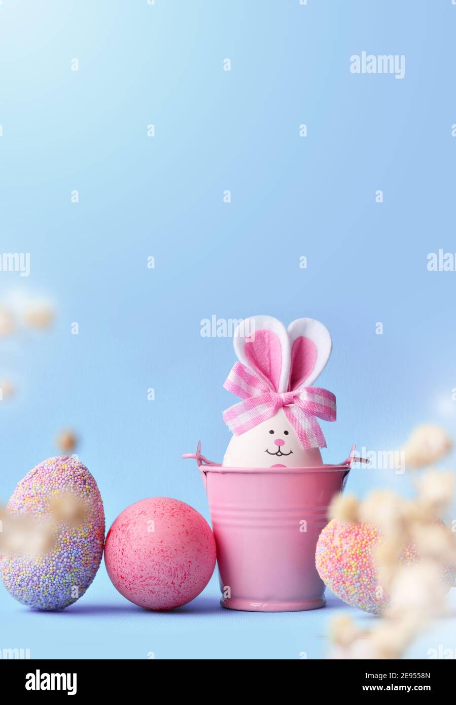 Concetto di festa di Pasqua con le uova fatte a mano carine, secchio e orecchie conigliate. Decorazione di festa di Pasqua. Foto Stock