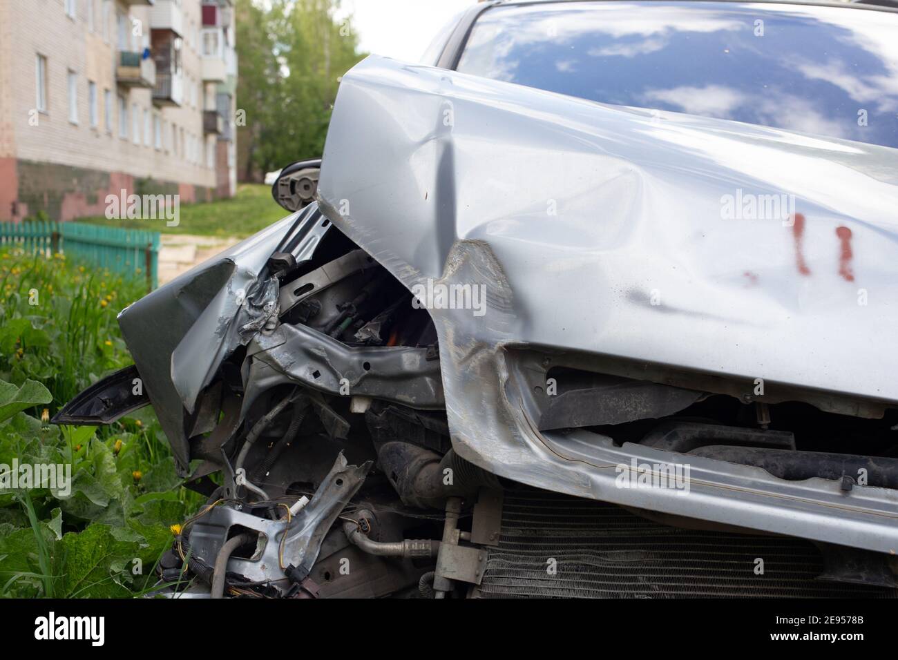 vista ravvicinata sul lato anteriore destro dell'auto argentata danneggiata fisicamente in caso di incidente stradale, primo piano con sfondo sfocato. Foto Stock