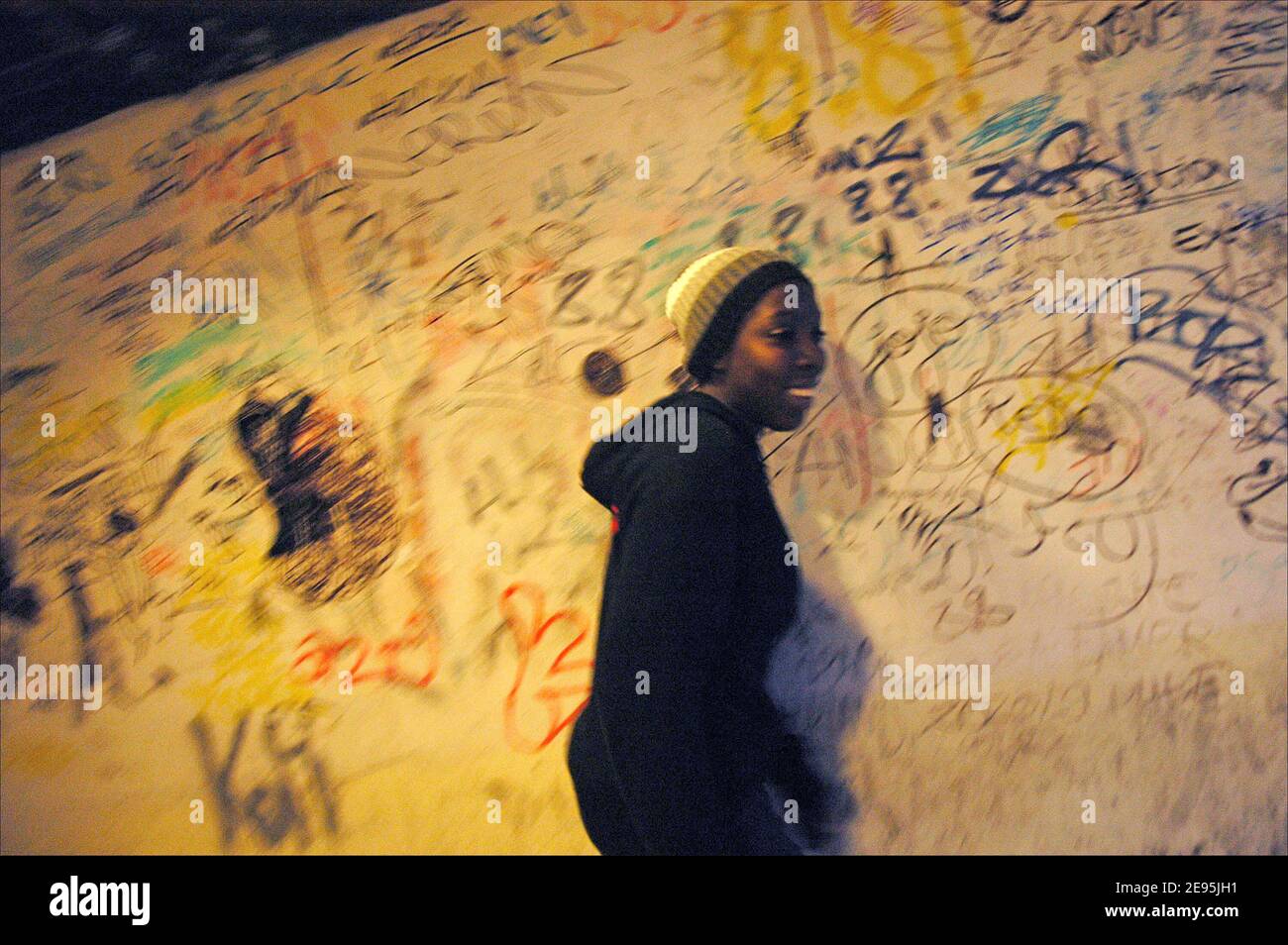 Un tenn-ager passeggiate di fronte a un muro coperto da graffiti muro nel 'Forestiere', che ospita comunità di Clichy-Sous-Bois, a nord di Parigi, Francia nel dicembre 2005. Qui iniziarono le rivolte dei massicci che bruciarono numerosi sobborghi francesi tre mesi fa, dopo che due giovani locali morirono quando cercarono di fuggire dai poliziotti. Foto di Axelle de russe/ABACAPRESS.COM Foto Stock