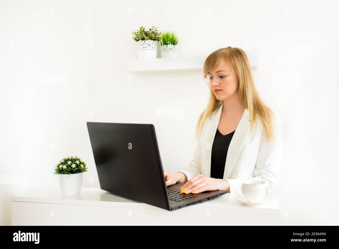 Remote work.Entrepreneur donna indossare giacca bianca lavorare con un computer portatile seduto su un divano a casa.consultazione online di un avvocato fiscale, contabile Foto Stock