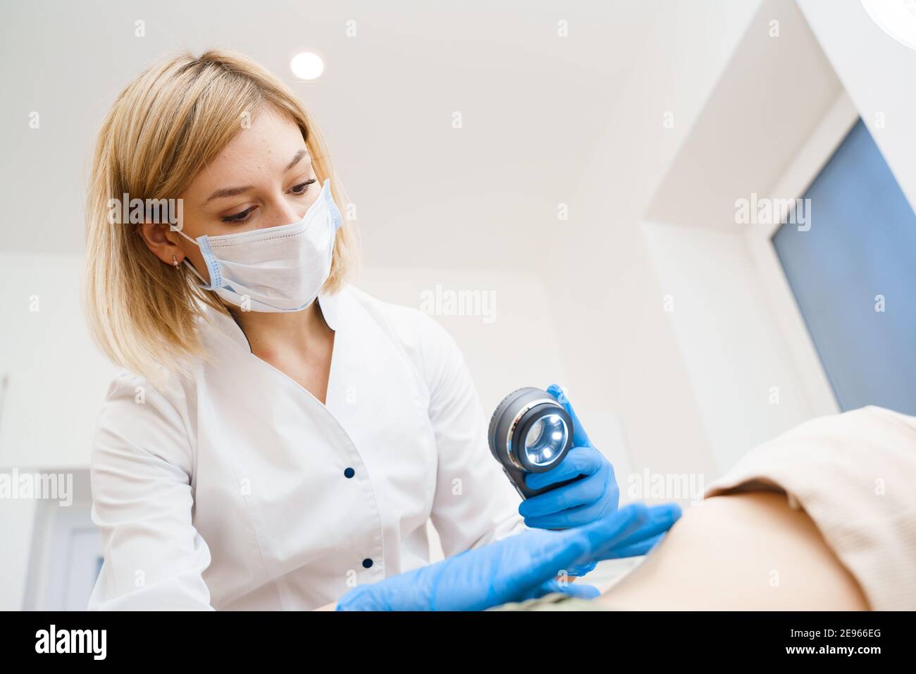 Il dermatologo effettua un esame utilizzando un dermatoscopio. Consultazione con un medico. Procedura di ringiovanimento Foto Stock
