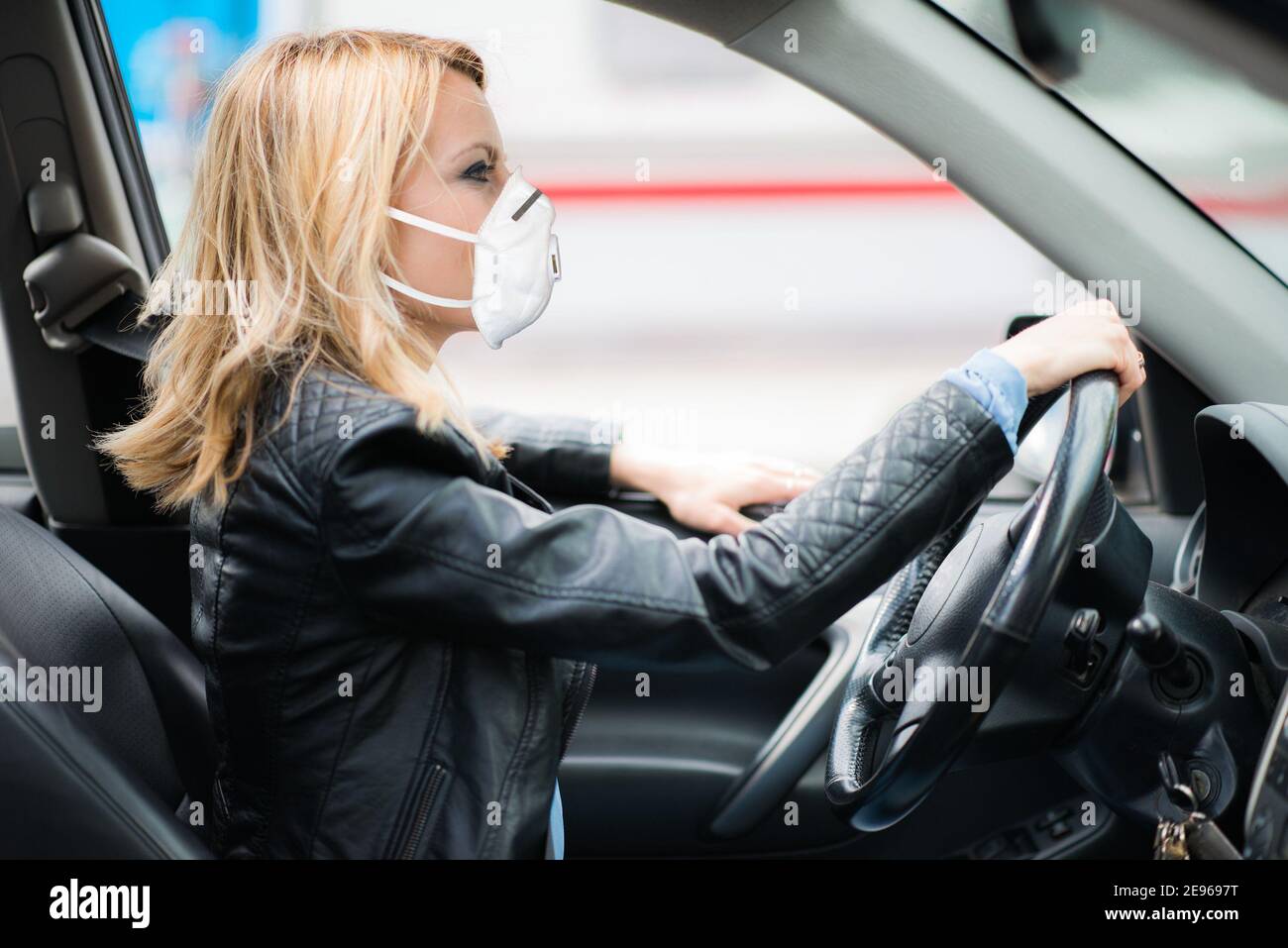 Donna guida auto mentre si indossa una maschera, coronavirus covid concetto Foto Stock