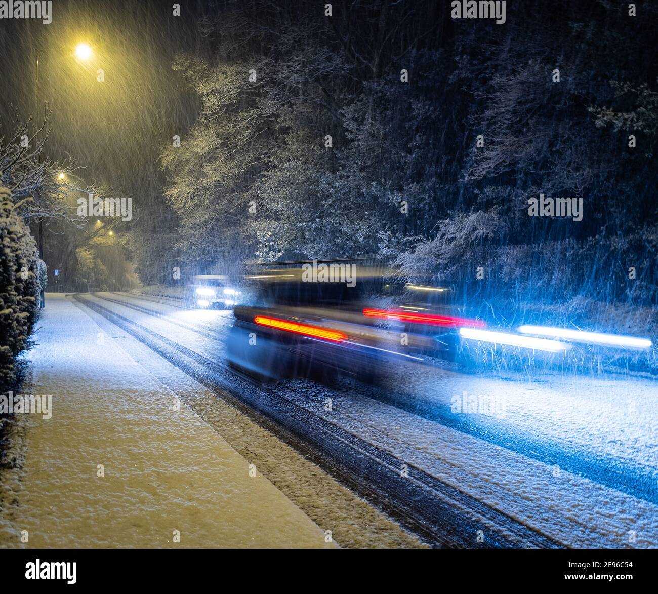 Auto che accelerano su strada ghiacciata britannica durante la nevicata pesante Foto Stock