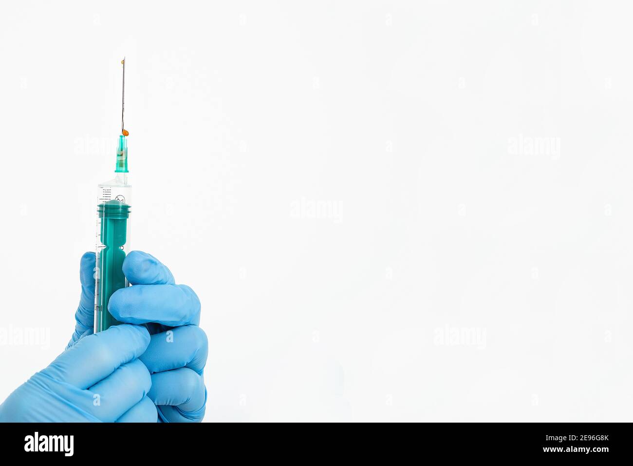 Una mano del medico in un guanto medico contiene una siringa con un ago per proteggere contro il virus dell'influenza. Vaccino CVD. Il concetto di vaccinazione medica Foto Stock