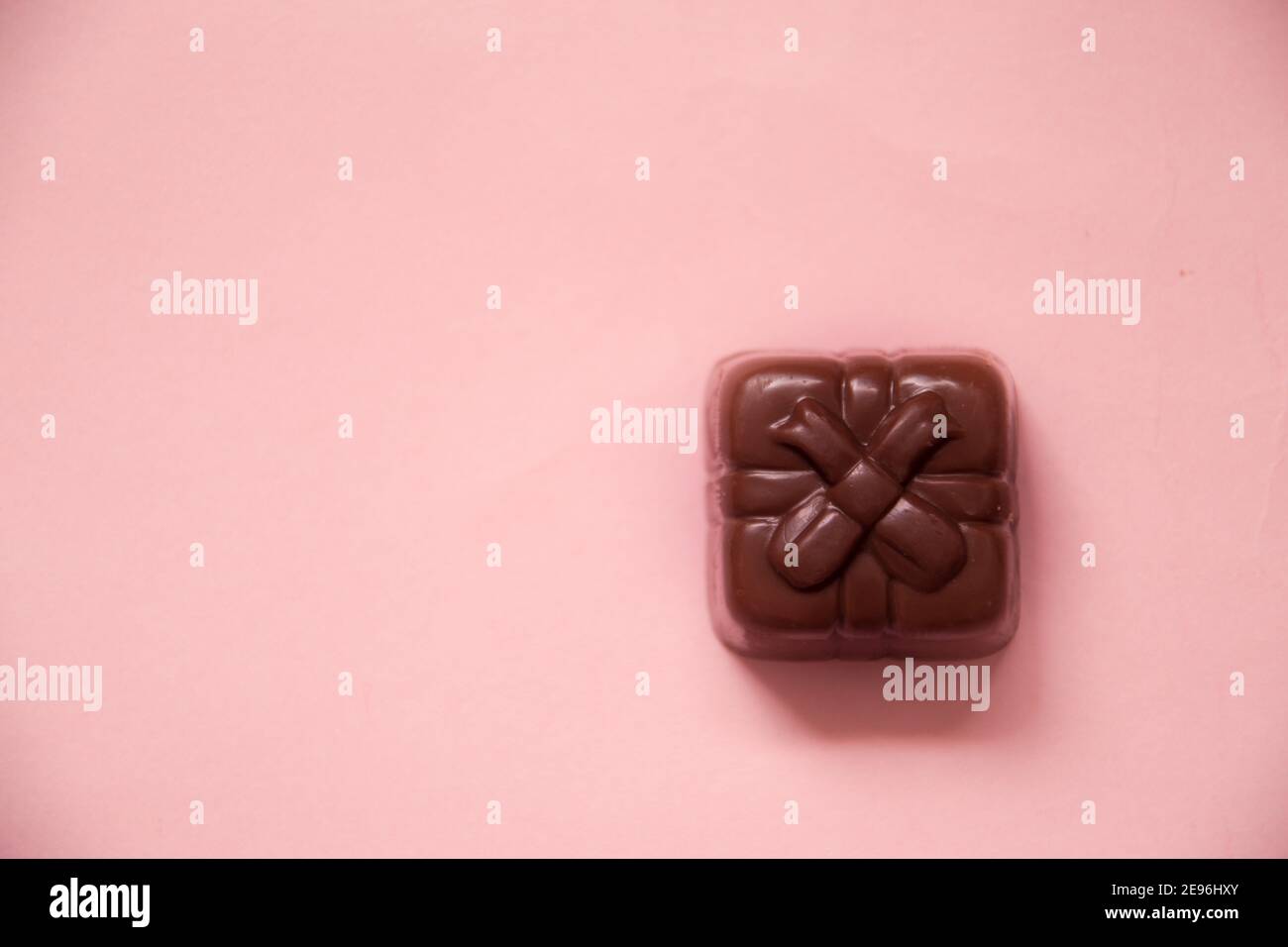Poco cioccolato di un regalo su una superficie rosa Foto Stock