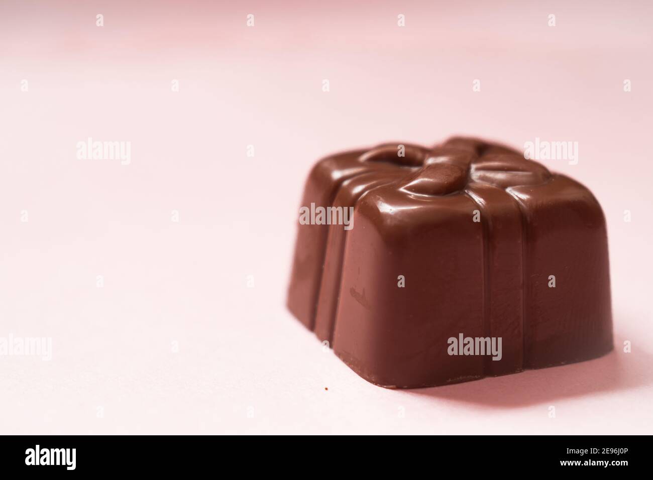 Poco cioccolato di un regalo su una superficie rosa Foto Stock