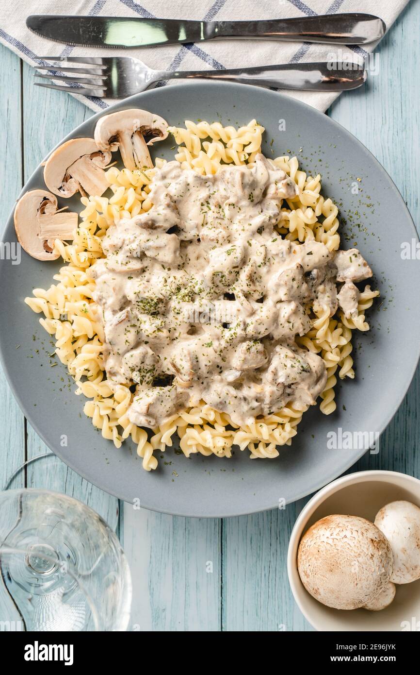 Tagliatelle con salsa cremosa ai funghi di champignon bianchi della foresta e pollo o carne di manzo - cibo fatto in casa in piatto sulla vista dall'alto del tavolo Foto Stock