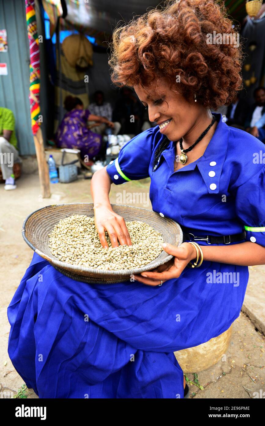 Una donna Tigray smistare i rifiuti dal mucchio di chicchi di caffè fresco ad Axum, Etiopia. Foto Stock