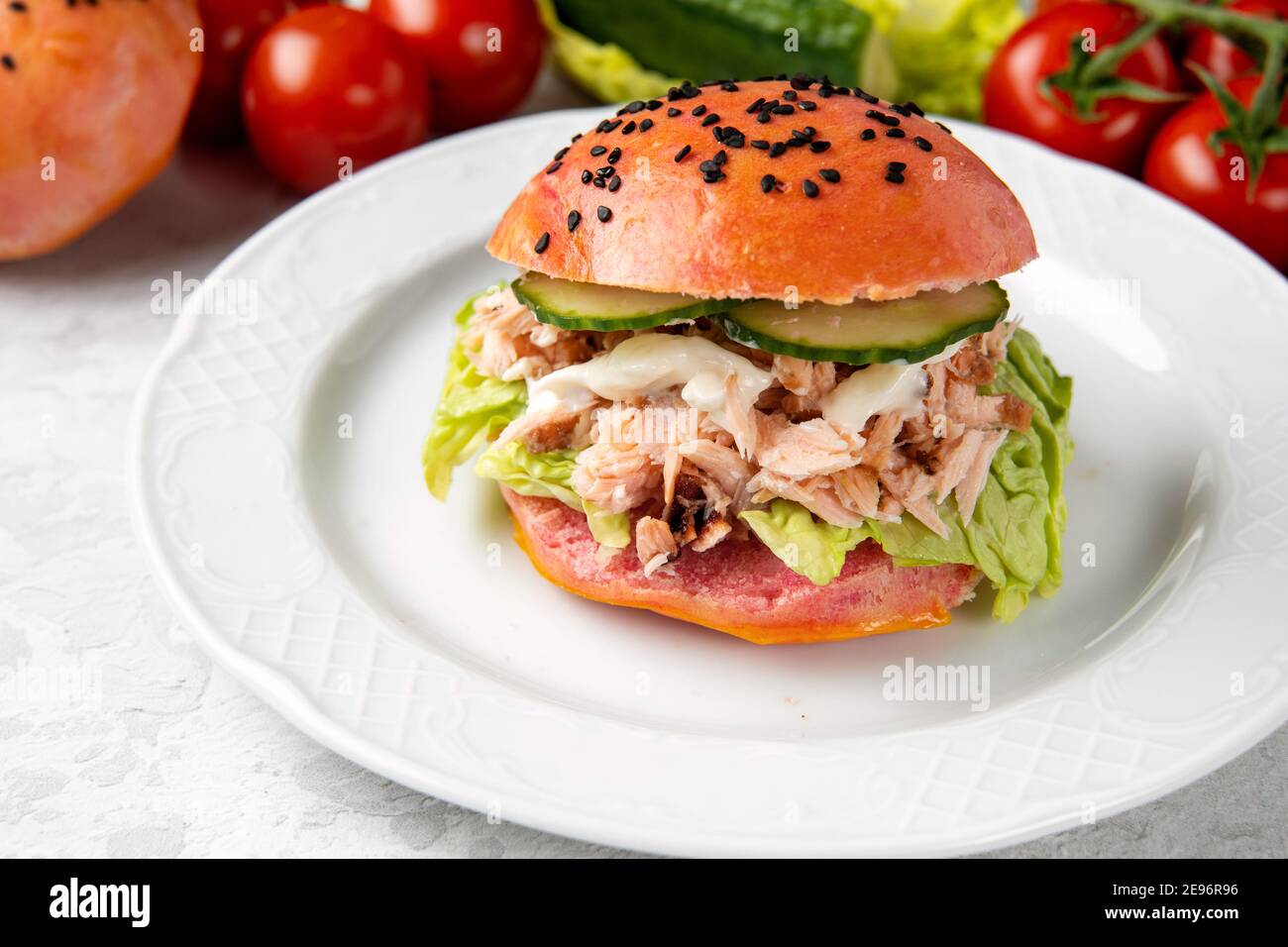 Delizioso hamburger di salmone con pasta rosa e pesce rosso una piastra bianca Foto Stock