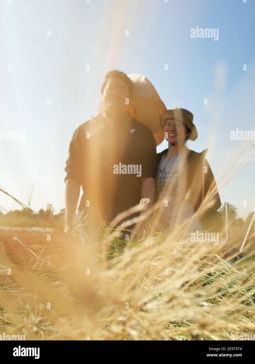 Immagine sfocata di una coppia che lavora insieme sul campo sotto il cielo blu. Foto Stock