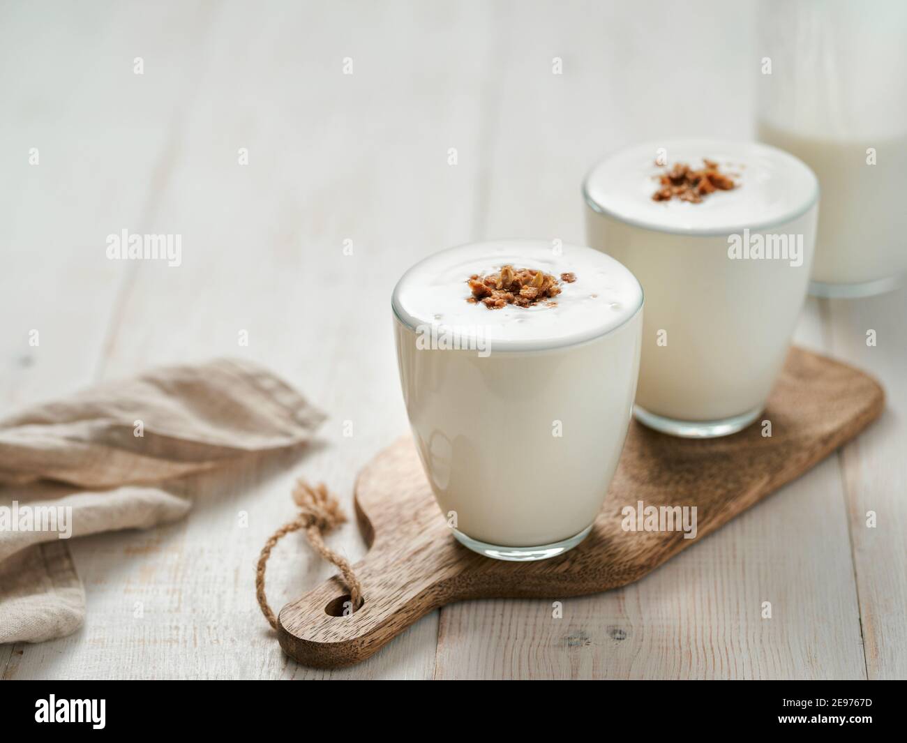 Kefir, latticello o yogurt con muesli. Yogurt in vetro su sfondo bianco di legno. Bevanda casearia fermentata a freddo probiotica. Salute intestinale, prodotti fermentati, concetto di flora intestinale sana. Spazio di copia Foto Stock