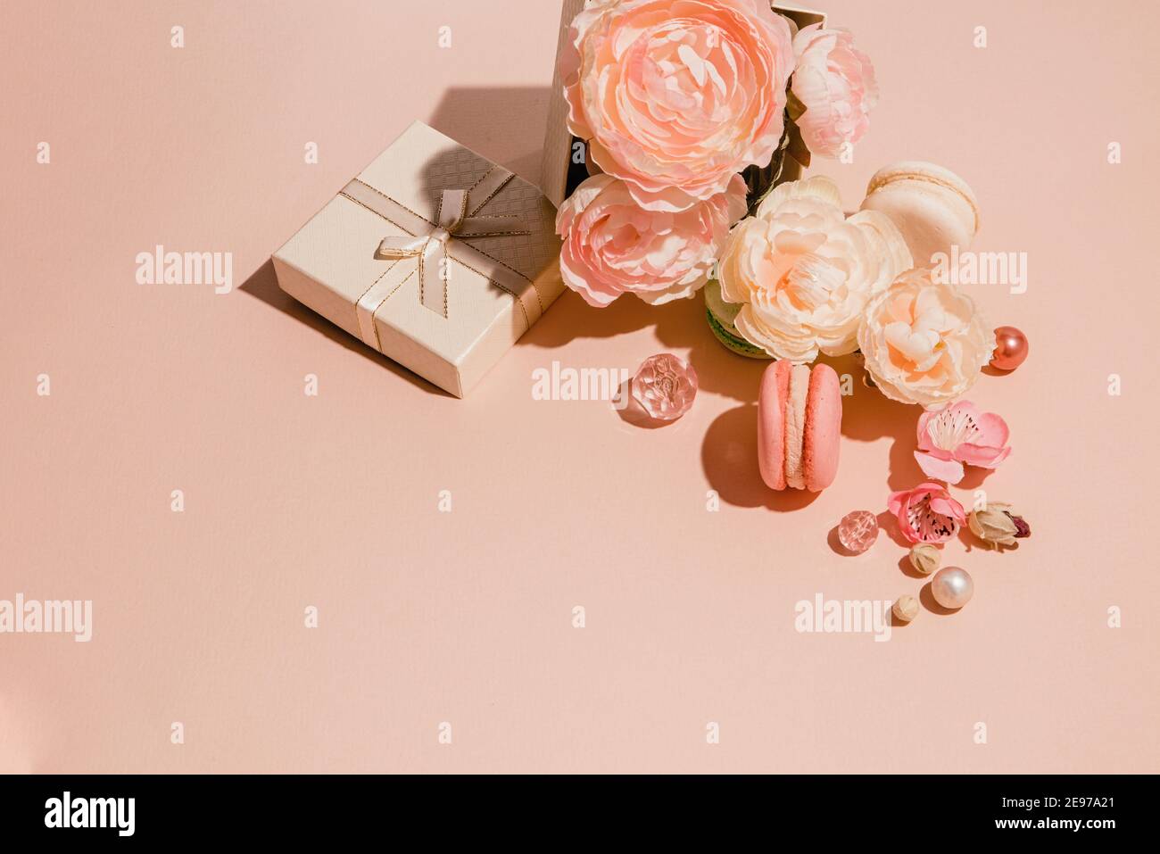 Composizione di fiori, regali e makaruns colori pastello di pesca monocromatici. Concetto trendy di primavera minimal Foto Stock