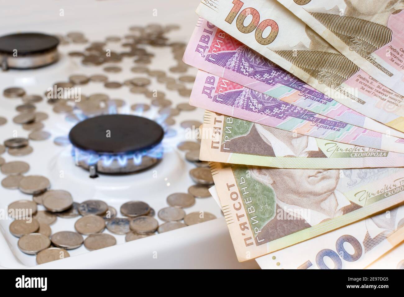 Hryvnias ucraino sullo sfondo di monete e bruciatori a gas sulla stufa. Prezzo del gas e delle utenze Foto Stock