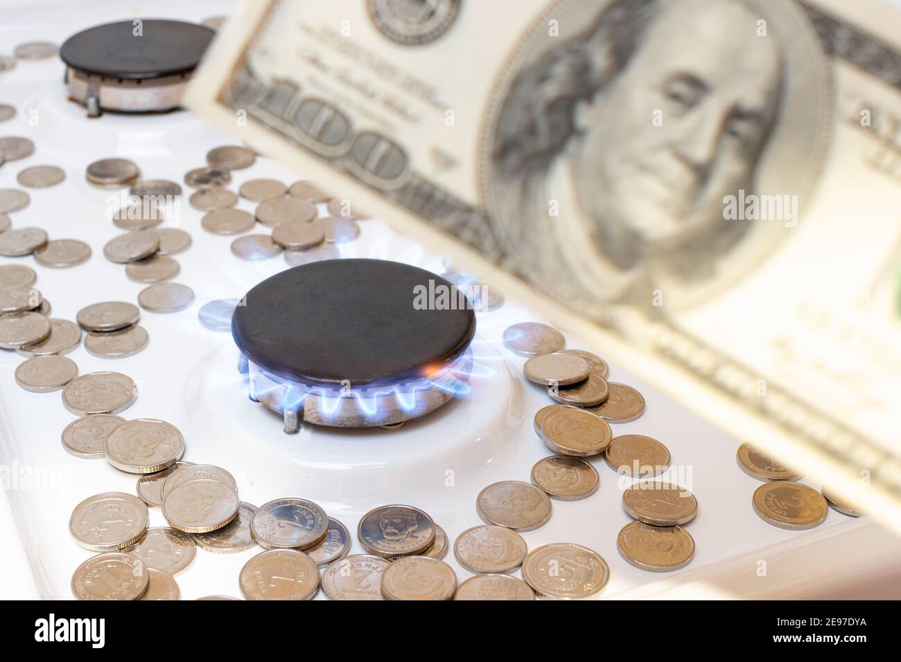 banconote da 100 dollari e bruciature di gas naturale nel bruciatore di una lastra con monete. Il costo del gas nel mondo. Foto Stock