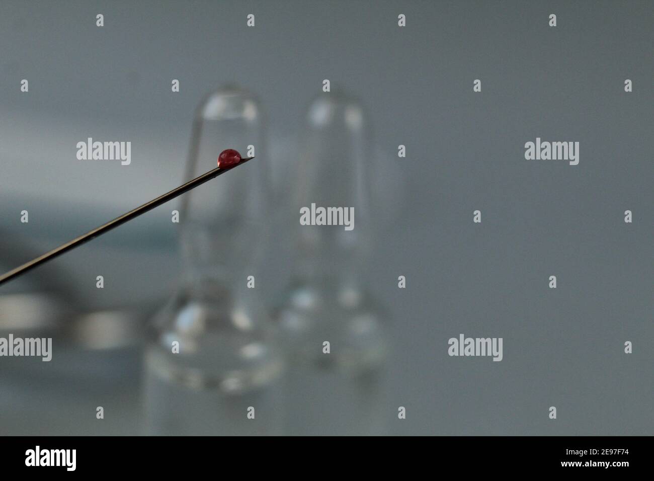 la vaccinazione rilascia il farmaco del sangue su un ago su uno sfondo blu con un copyspace. Foto Stock