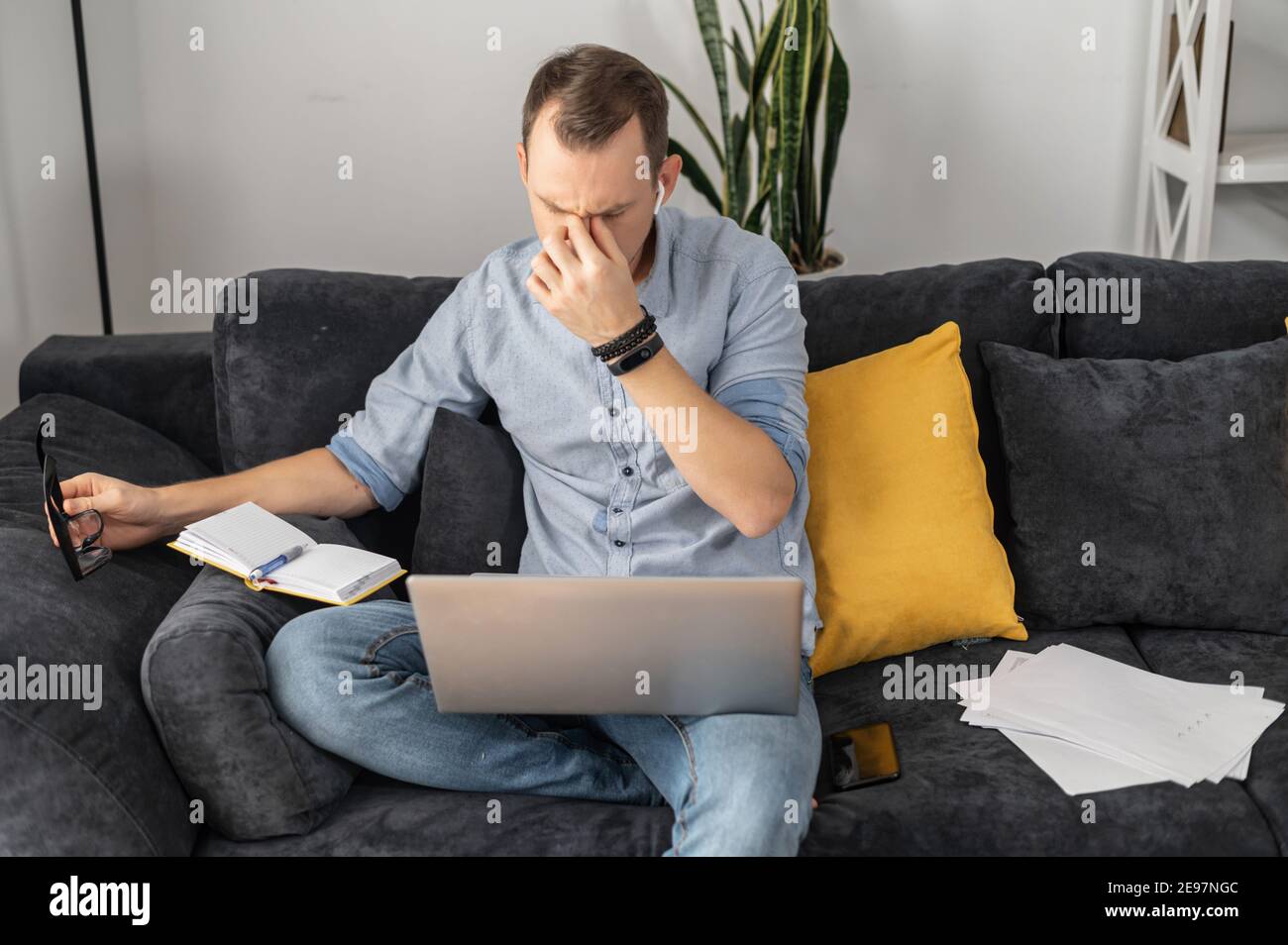 Uomo d'affari overlavored in abiti casual intelligenti lavora da casa, togliere occhiali e occhi chiusi, tenendo e massaggiando il suo ponte nasale, sofferente Foto Stock
