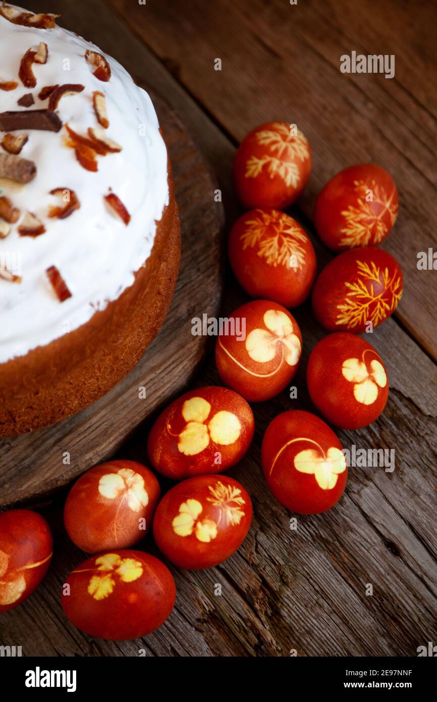 Torta di Pasqua e uova colorate. Cibo rustico su un tavolo di legno. Uovo tradizionale colorato con buccia di cipolla. Modello di foglie di trifoglio e aneto. Cibo classico per Foto Stock