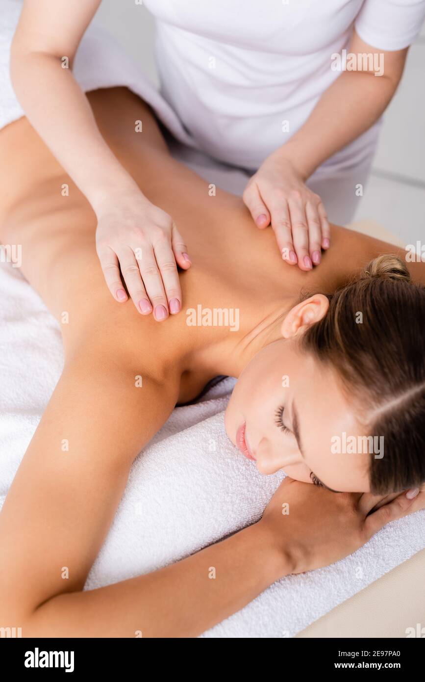 massaggiatrice femminile che massaggia la parte posteriore del cliente sdraiata sul tavolo da massaggio Foto Stock