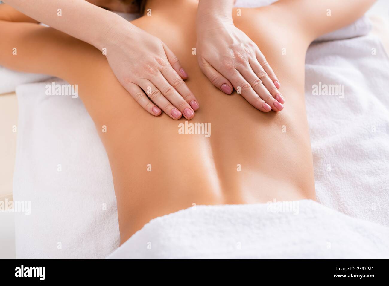 vista parziale del massaggiatore che massaggiano la parte posteriore del cliente sdraiato tavolo massaggiante Foto Stock