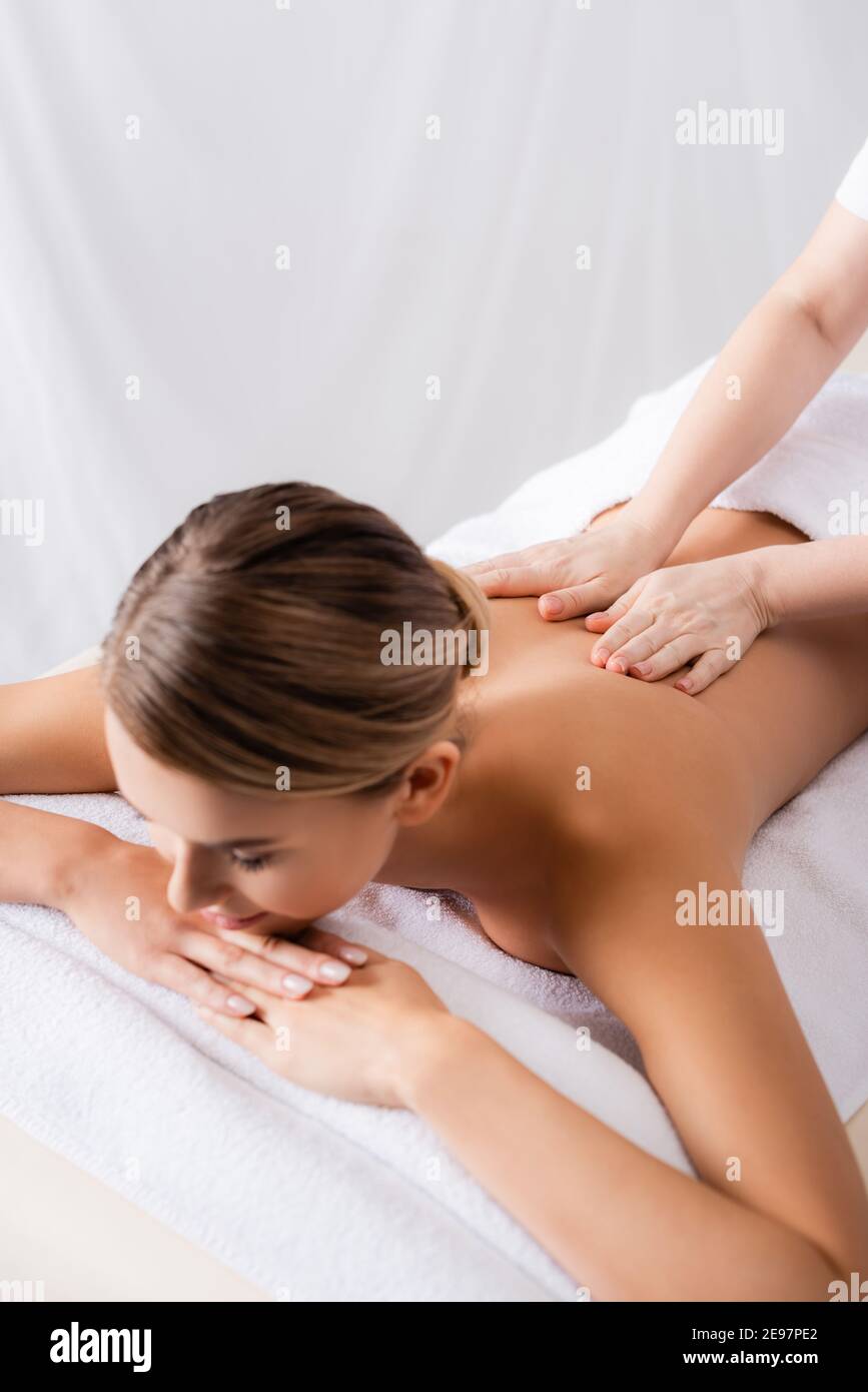 massaggiante massaggiante sul retro del cliente sdraiato sul tavolo da massaggio Foto Stock
