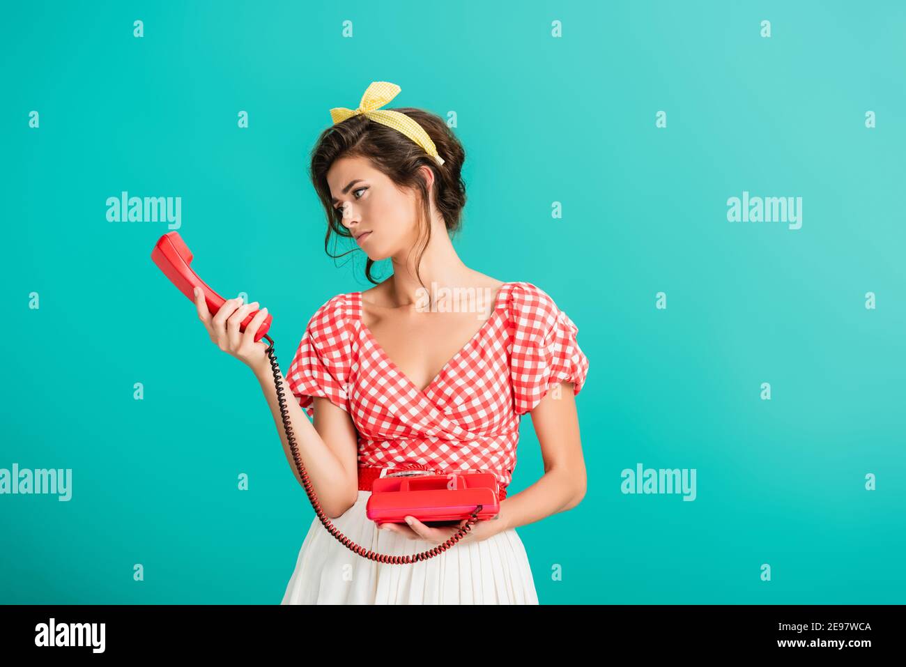 offended pin su donna che tiene il microtelefono di telefono vintage isolato su turchese Foto Stock