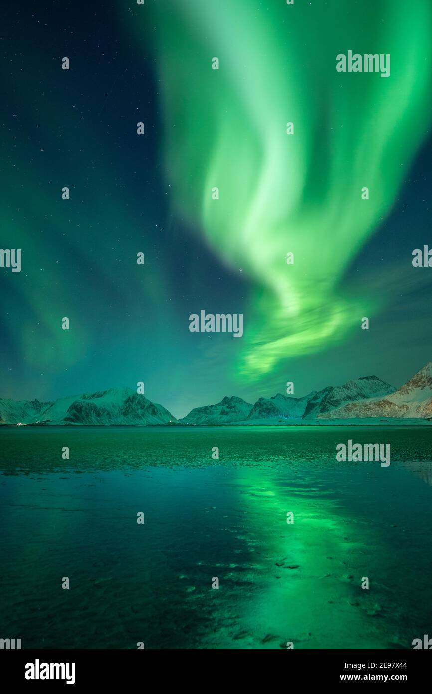 Aurora boreale sopra le montagne delle isole Lofoten. Riflessioni di Aurora Borealis sulla spiaggia sabbiosa di Sandbotnen. Belle condizioni invernali a nort Foto Stock